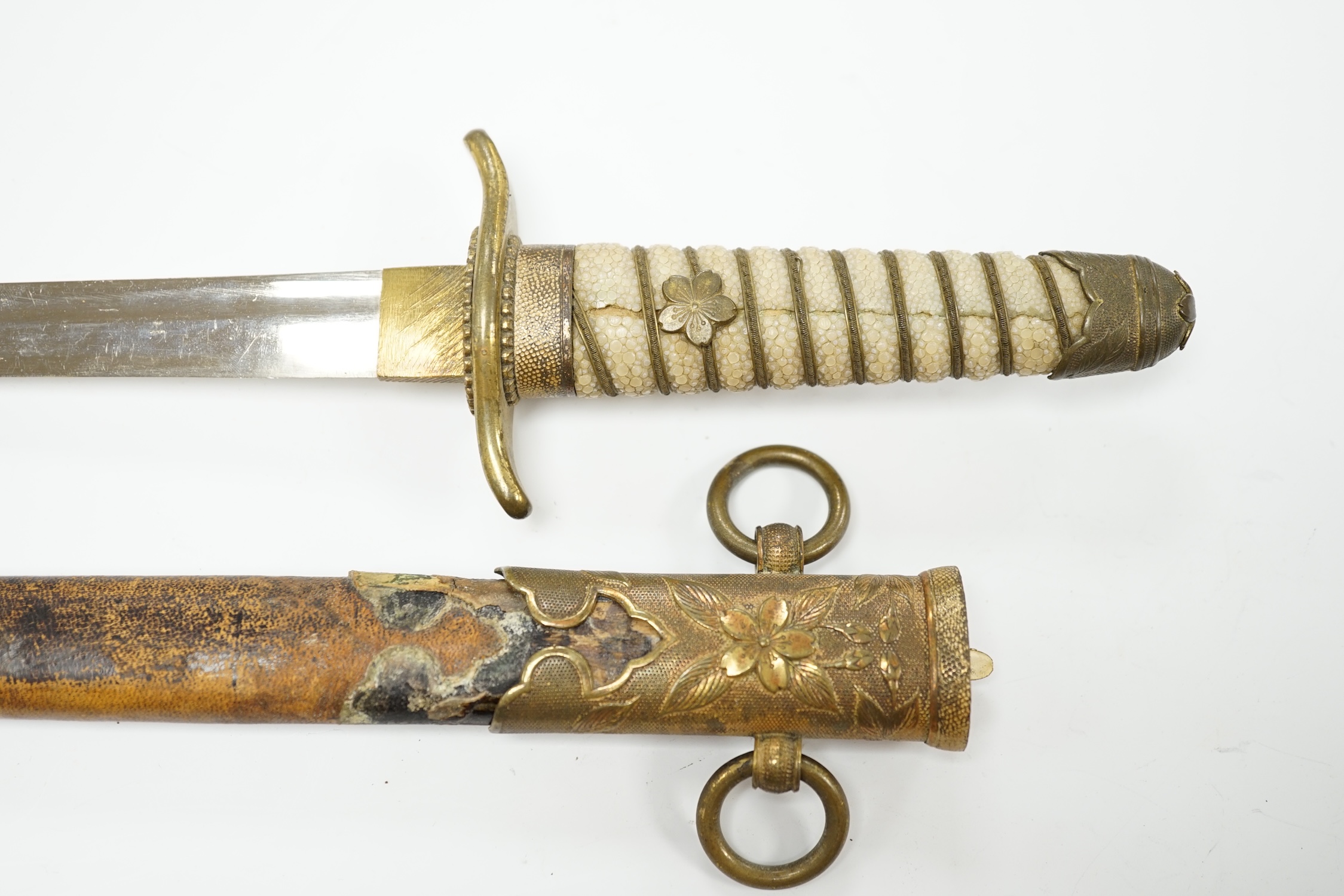 A dagger with brass fittings and a shagreen grip, in a leather covered scabbard, blade 21cm. Condition - losses to leatherwork and scabbard, splits to shagreen grip and some wear overall.